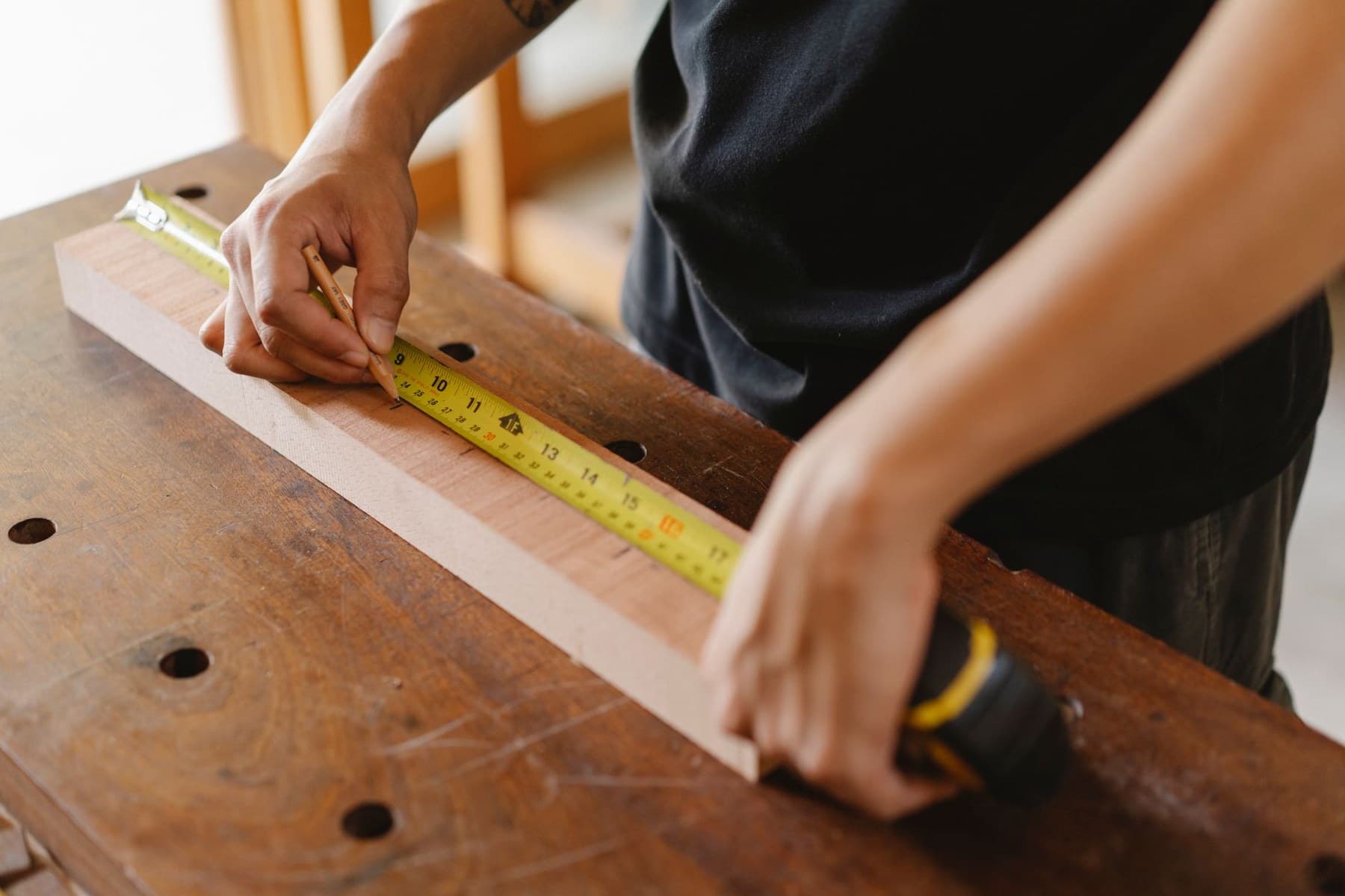 Representative carpenter measuring a wood member before layout and assembly