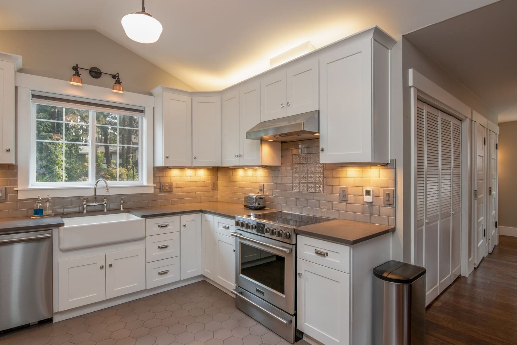 Representative modern kitchen with white cabinetry, island, countertop, and lighting